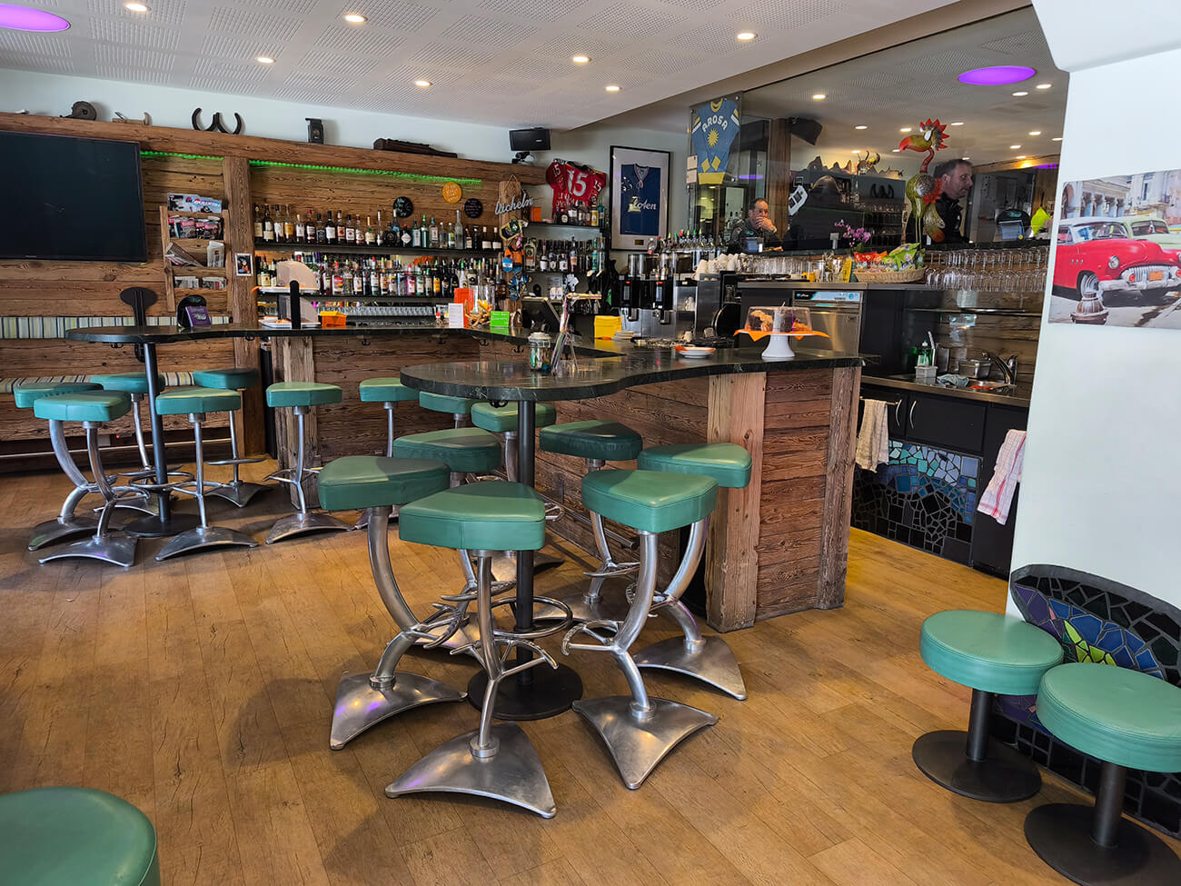 Blick auf die Overtime Bar Theke mit Barhocker und Backbar. Im Hintergrund sieht man ins Fumoir.